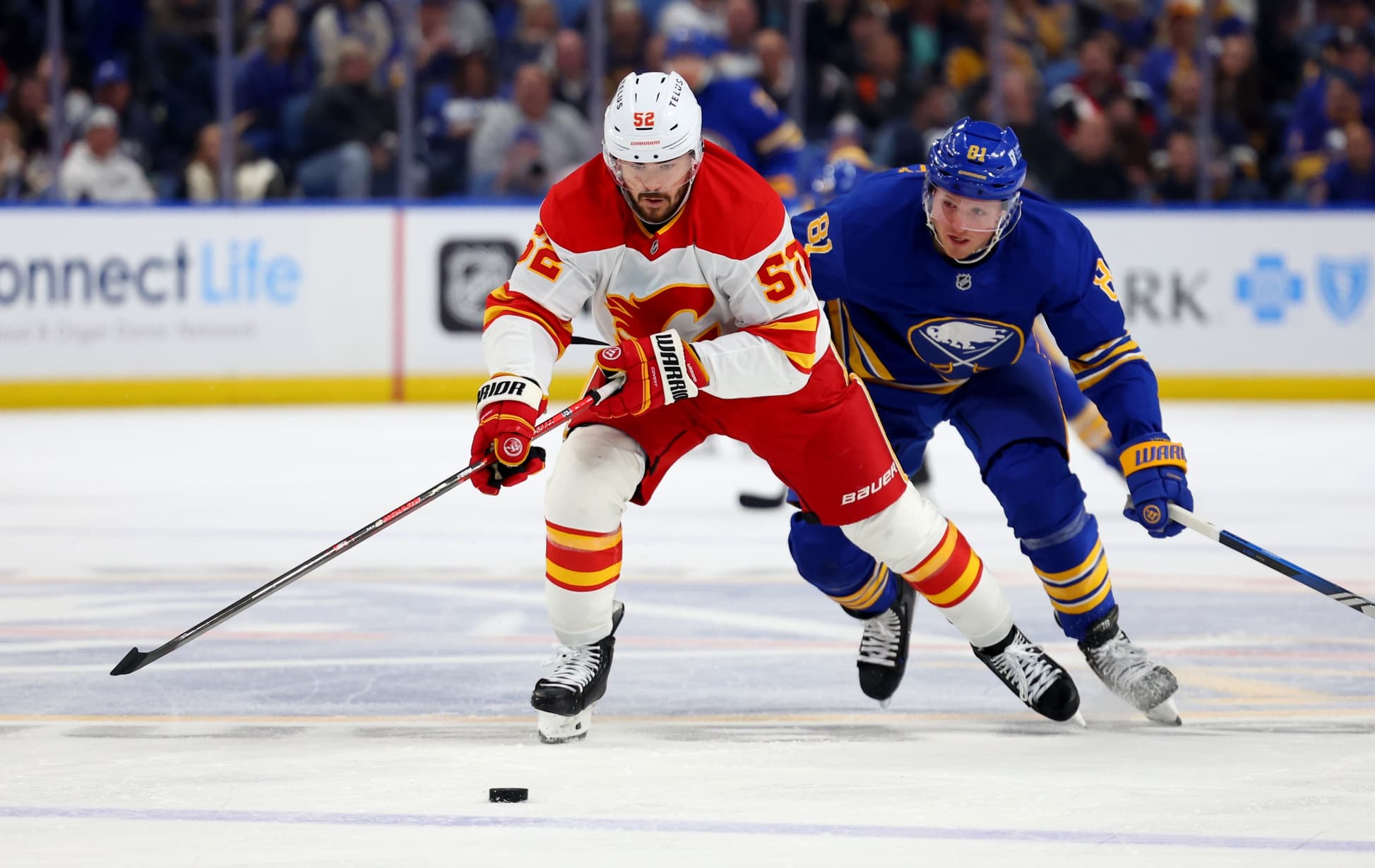 Calgary Flames defenseman MacKenzie Weegar (52) and Buffalo Sabres center Sam Lafferty (81) skate for a loose puck during the second period at KeyBank Center.