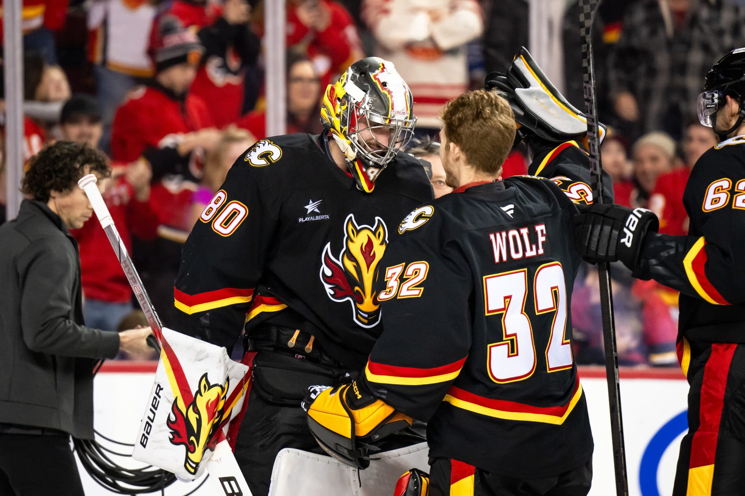 Calgary Flames goaltender Daniel Vladar (80) and goaltender Dustin Wolf (32) celebrate after a shootout victory over the Minnesota Wild at Scotiabank Saddledome