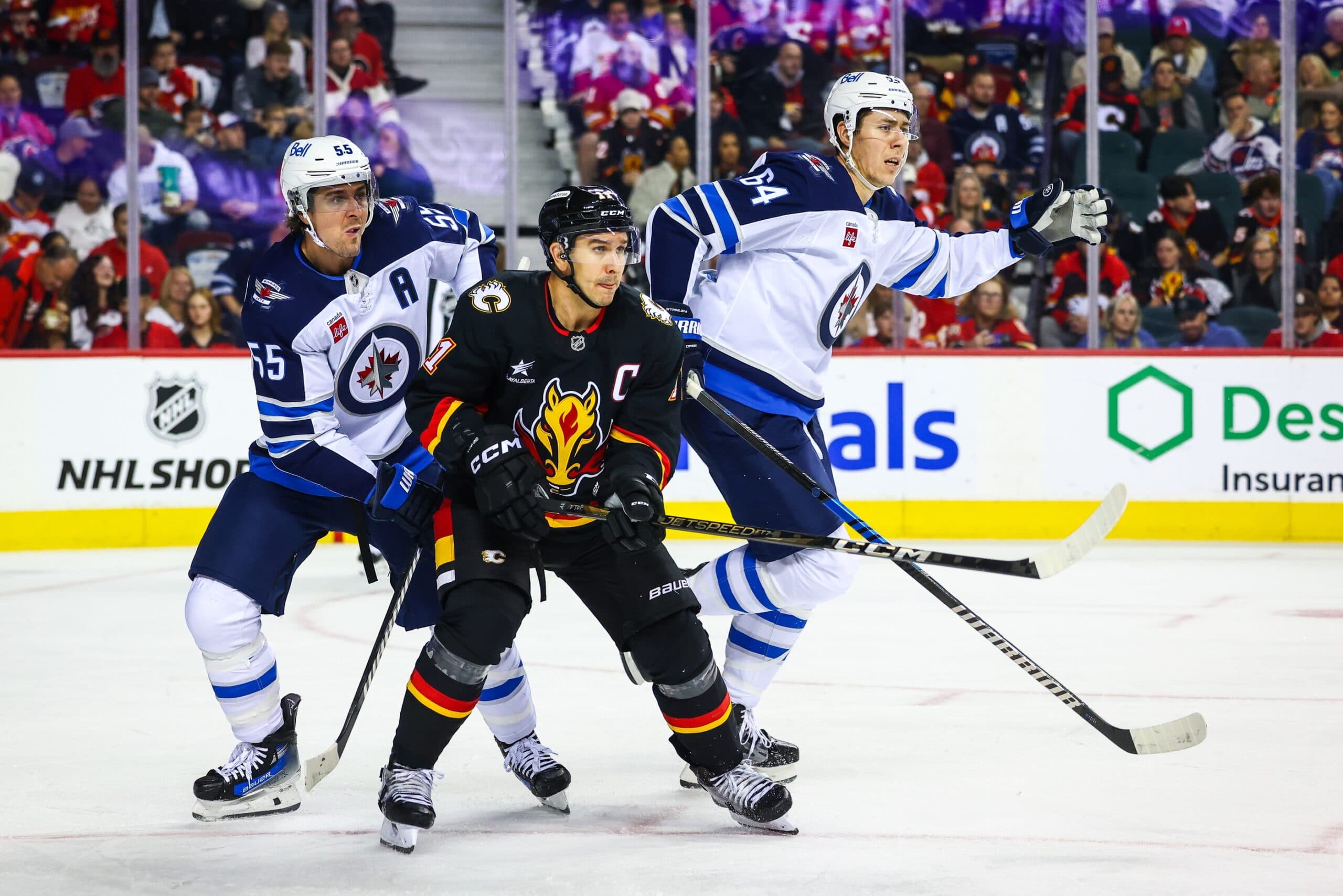 Calgary Flames center Mikael Backlund (11) and Winnipeg Jets center Mark Scheifele (55) fights for position during the second period at Scotiabank Saddledome.