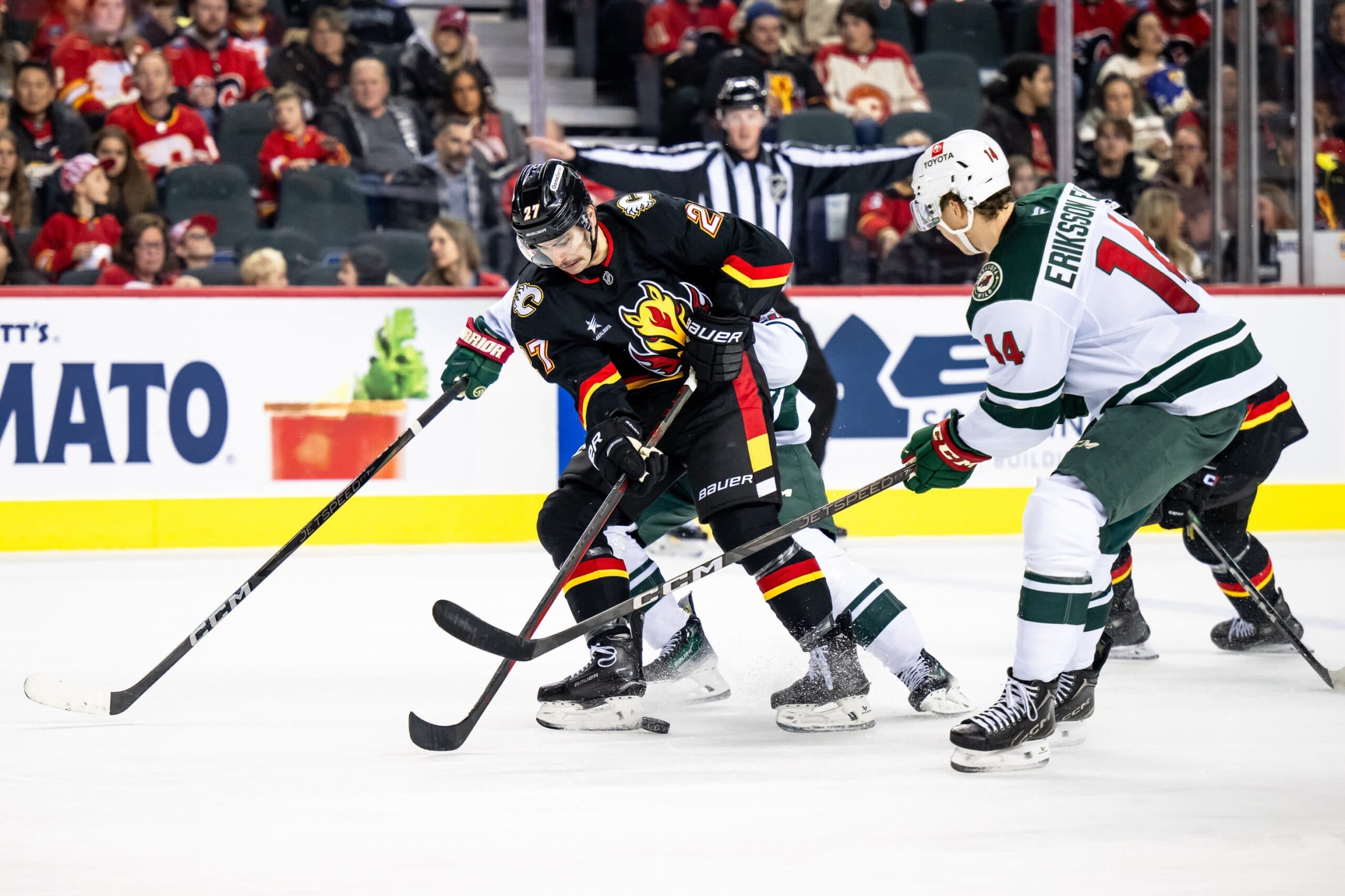 Calgary Flames right wing Matt Coronato (27) skates with the puck against Minnesota Wild center Joel Eriksson Ek (14) during the second period at Scotiabank Saddledome.