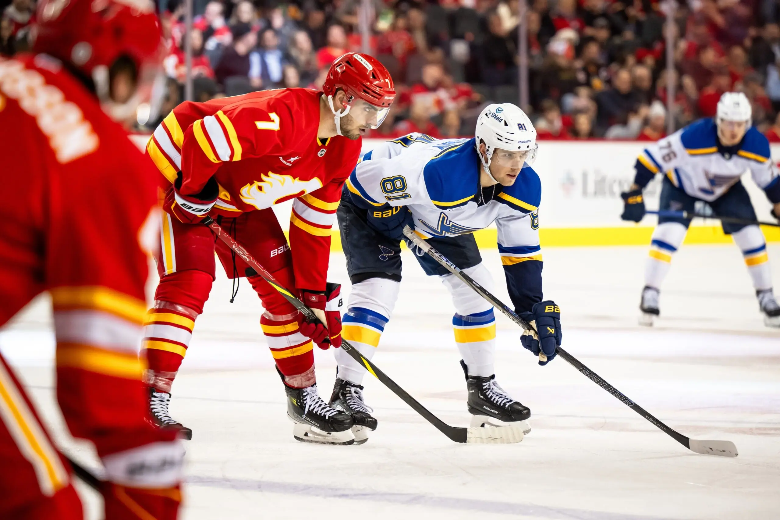 Calgary Flames defenseman Kevin Bahl (7) and St. Louis Blues left wing Dylan Holloway (81) get ready for a faceoff during the third period at Scotiabank Saddledome.