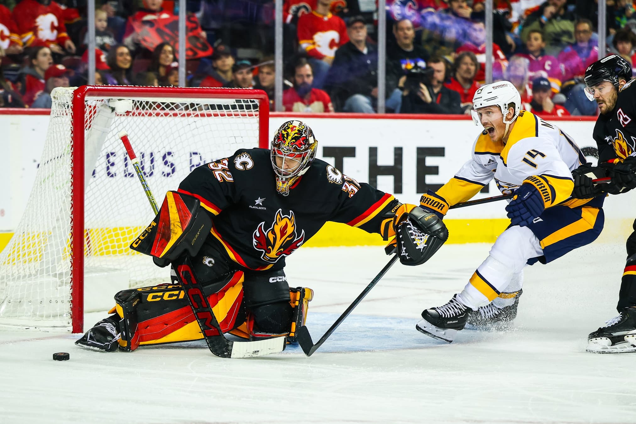 Calgary Flames goaltender Dustin Wolf (32) makes a save against Nashville Predators center Gustav Nyquist (14) during the third period at Scotiabank Saddledome