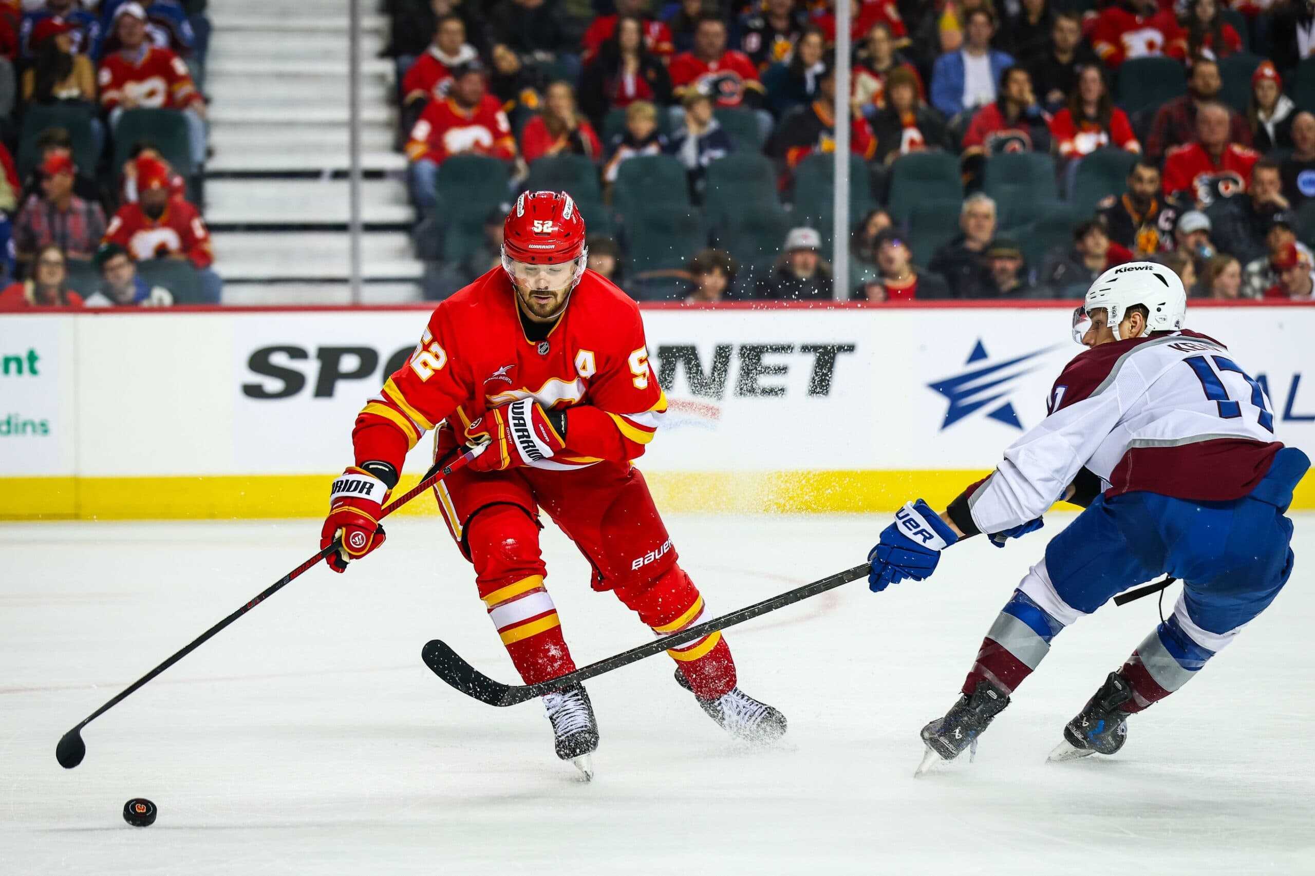 Calgary Flames defenseman MacKenzie Weegar (52) and Colorado Avalanche center Parker Kelly (17) battles for the puck during the third period at Scotiabank Saddledome